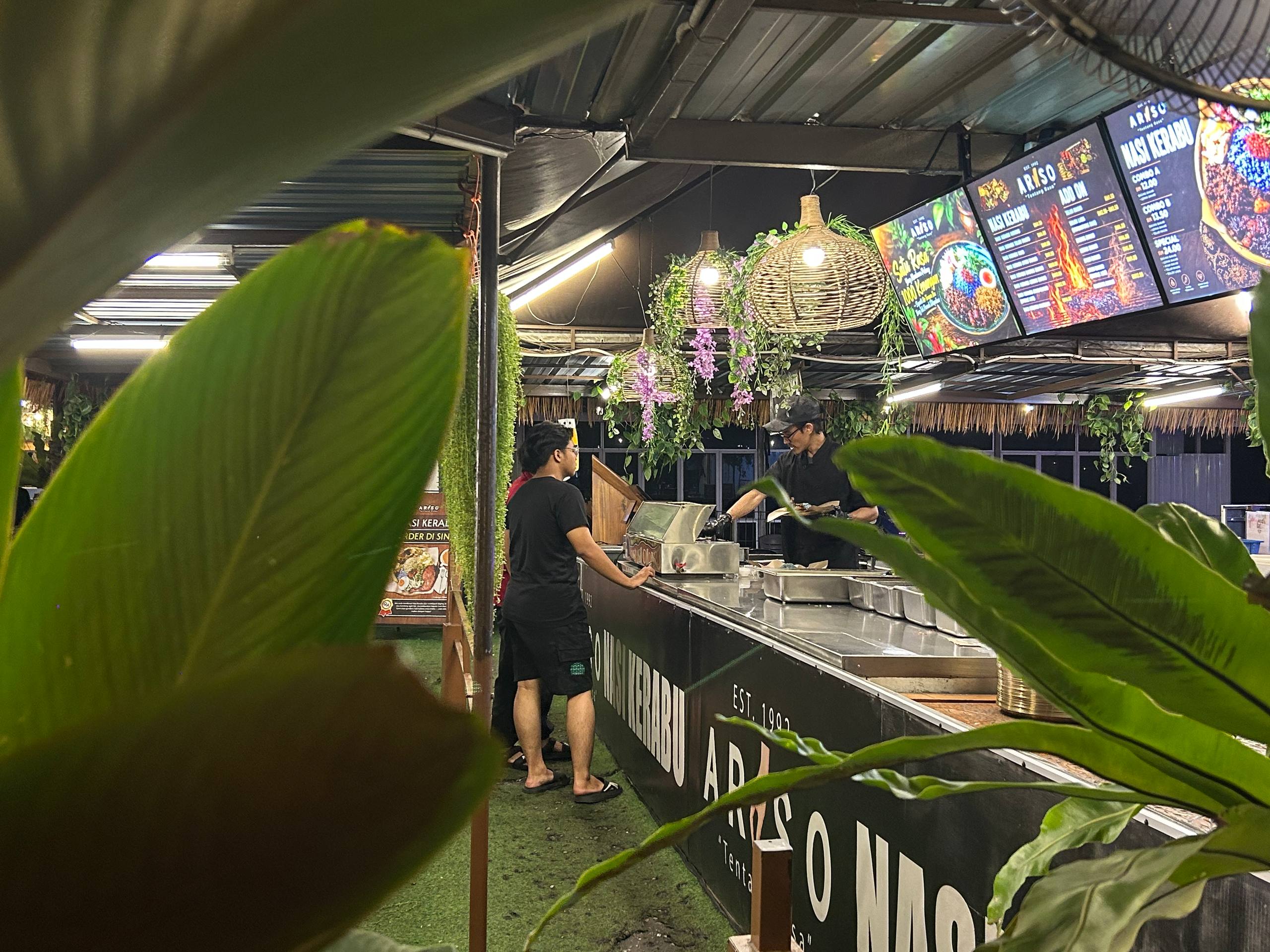 Nasi Kerabu service counter framed by tropical leaves